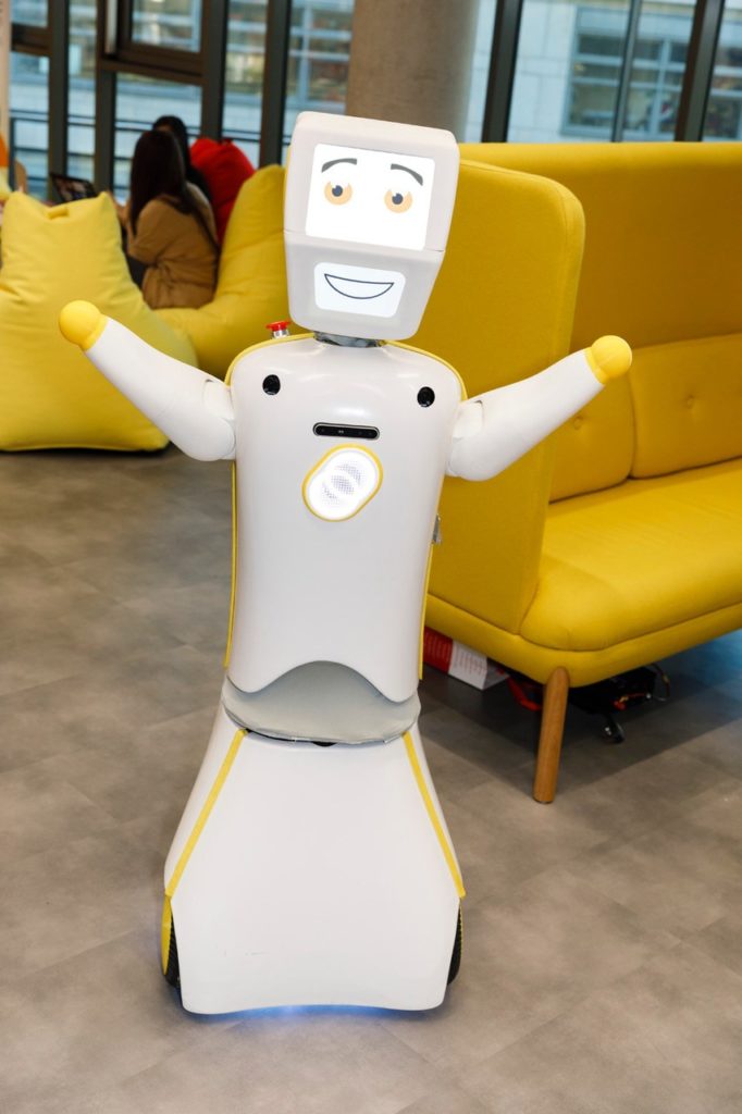 The humanoid robot Stevie raises his arms and smiles