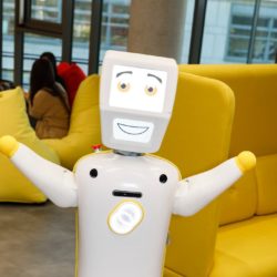 The humanoid robot Stevie raises his arms and smiles